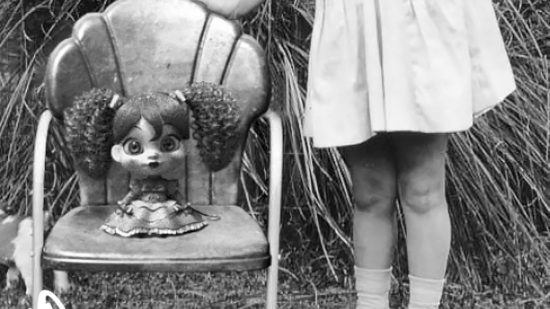 若い女の子のそばの椅子に座っているポピー プレイタイム ポピーの昔ながらの写真