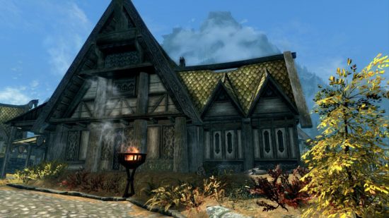 Skyrim の結婚: Skyrim のスクリーンショットで外に火灯籠のある家。 背の高い青い空を背景に、家は中世風です。