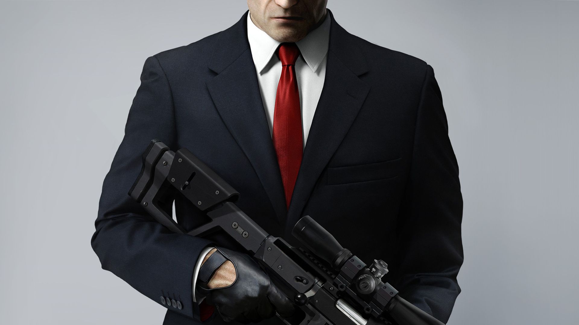 FPS ゲーム - 黒いスーツ、赤いネクタイ、白いシャツを着た男性が、スナイパー ライフルをまっすぐ前に向け、顔がフレームで切り取られています。