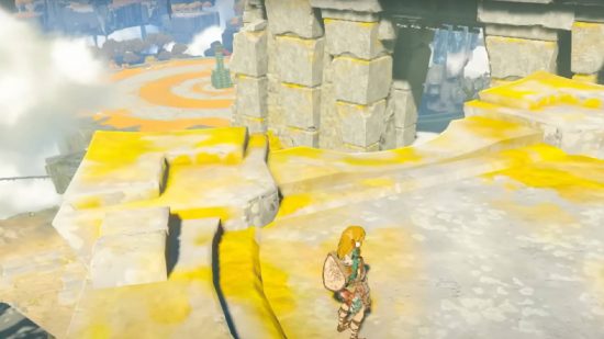 Zelda Tears of the Kingdom 予告編の内訳: リンクはオープン エリアに立っていますが、背景にはブロックで作られた構造物が赤いレーザーの目でスキャンしています。