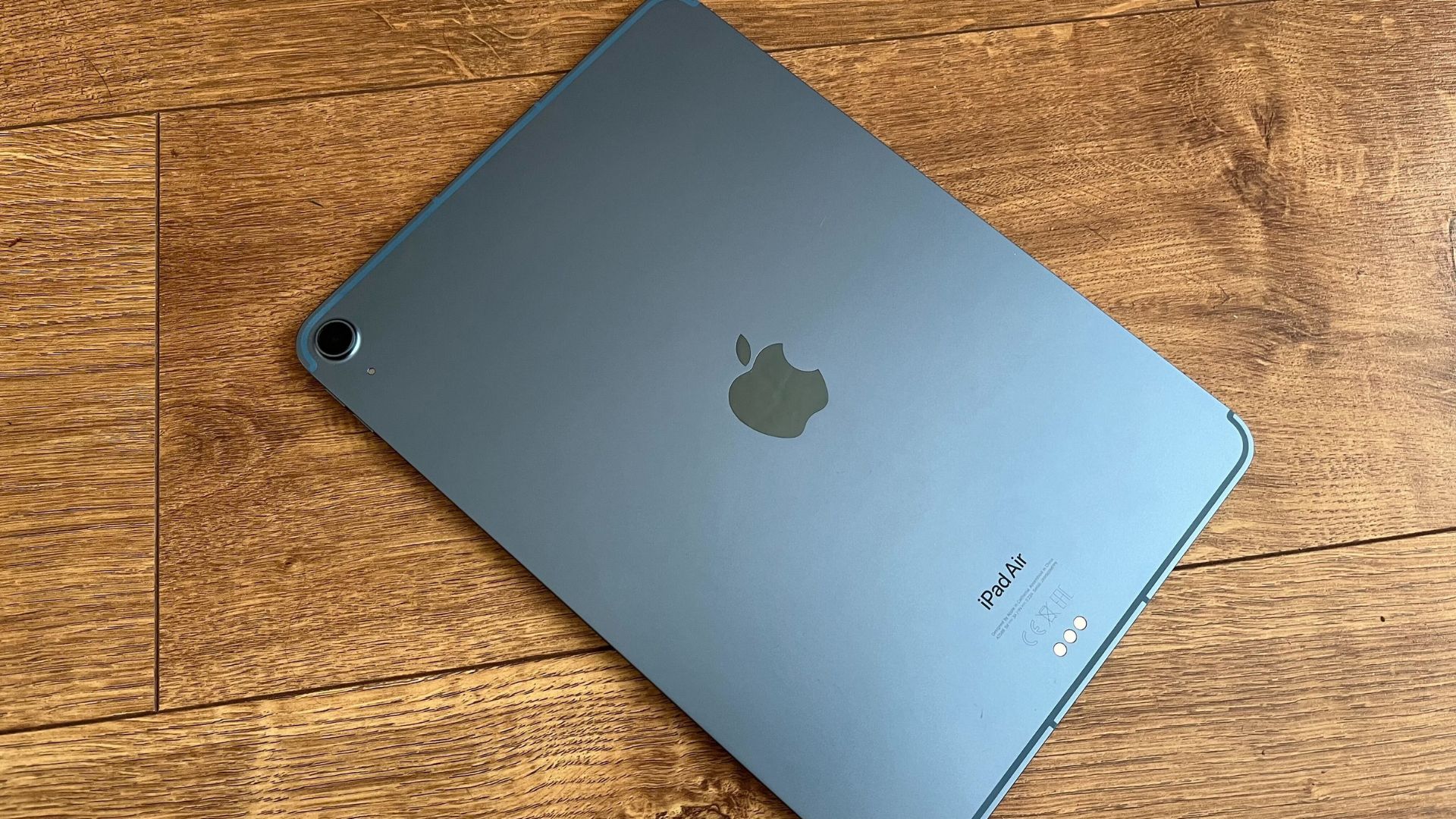 最高の iPad の 1 つである iPad Air は、黒色で、画面が木製の表面に置かれていました。 中央にAppleのロゴがあり、右上隅に小さな単一のカメラリングが表示されています。