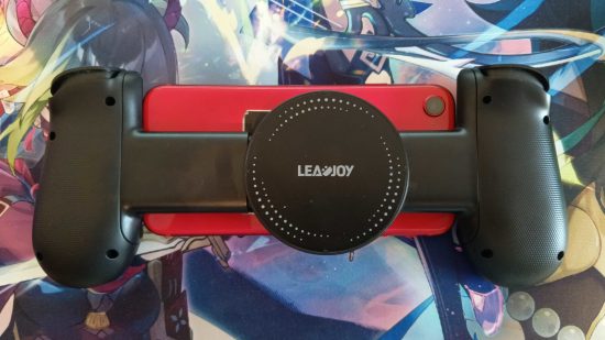LeadJoy M1 レビュー: 赤い iPhone SE に取り付けられた LeadJoy M1 コントローラーの背面。冷却プレートが見えています。 これは原神のマウスマットの上にあります。